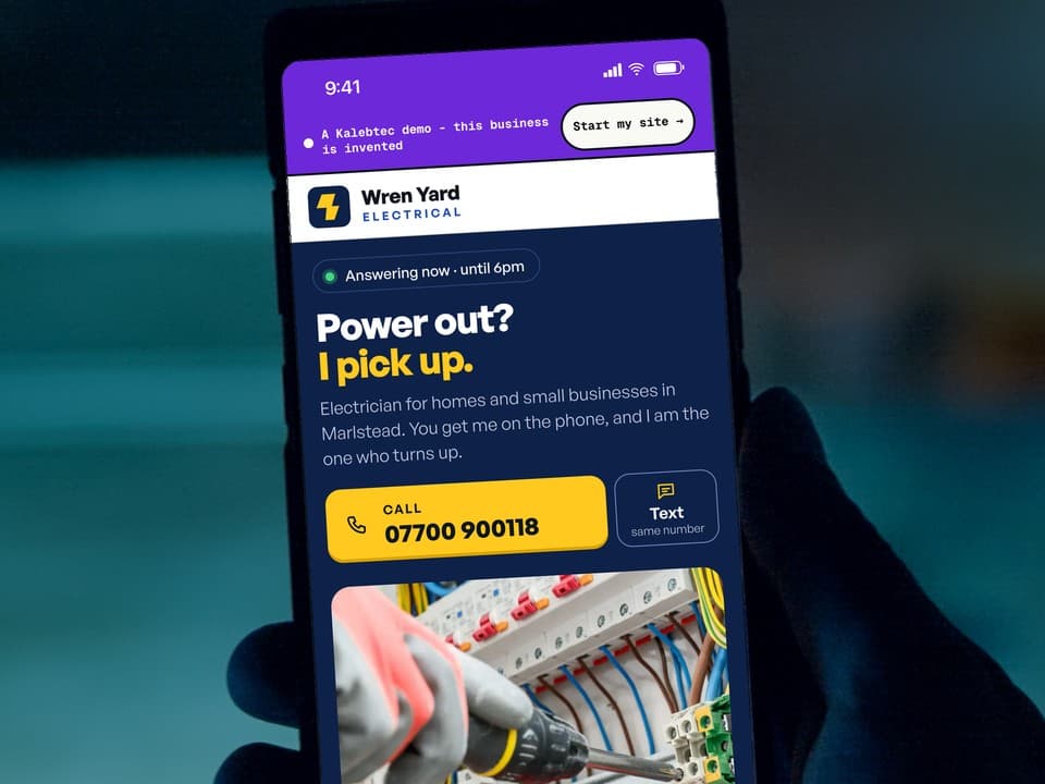 A phone open on the first screen of the Wren Yard Electrical demo: the headline "Power out? I pick up.", a yellow call button, and gloved hands at an open consumer unit.