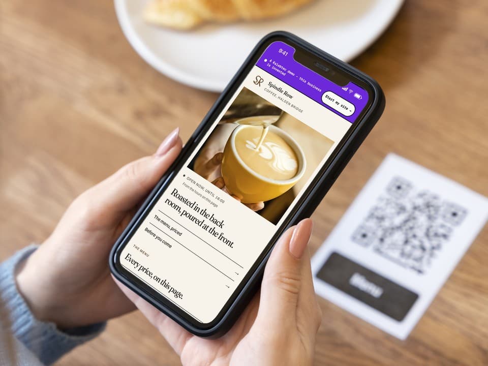 A phone open on the first screen of the Spindle Row Coffee demo: a photograph of the espresso counter, the headline "One long room, and no music before eight.", and a link to the priced menu.